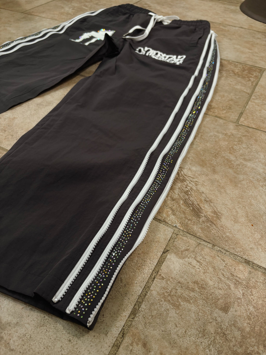 Black tracksuit with white stripes on a tiled floor
