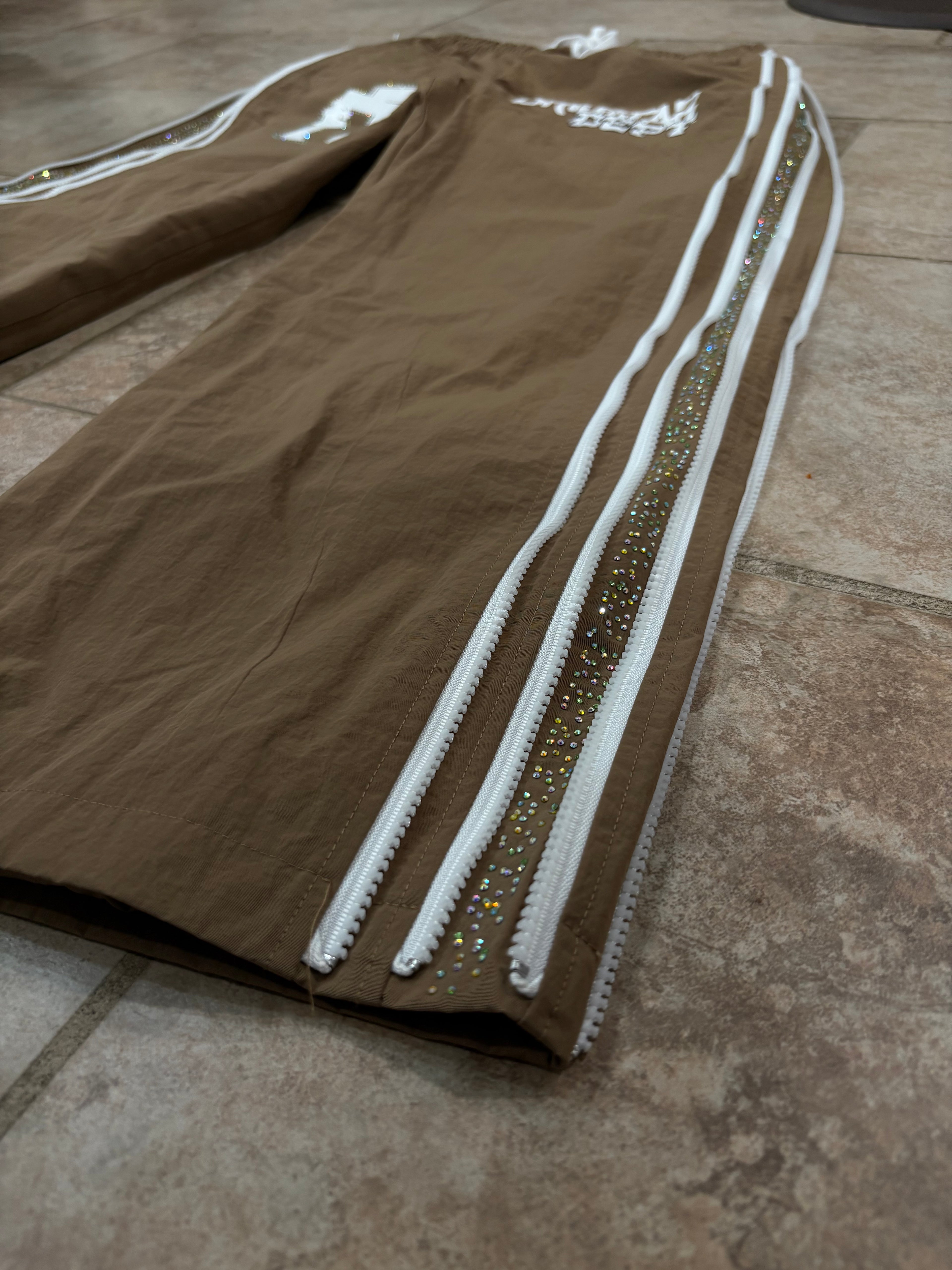 Brown pants with glittery stripes on a tiled floor